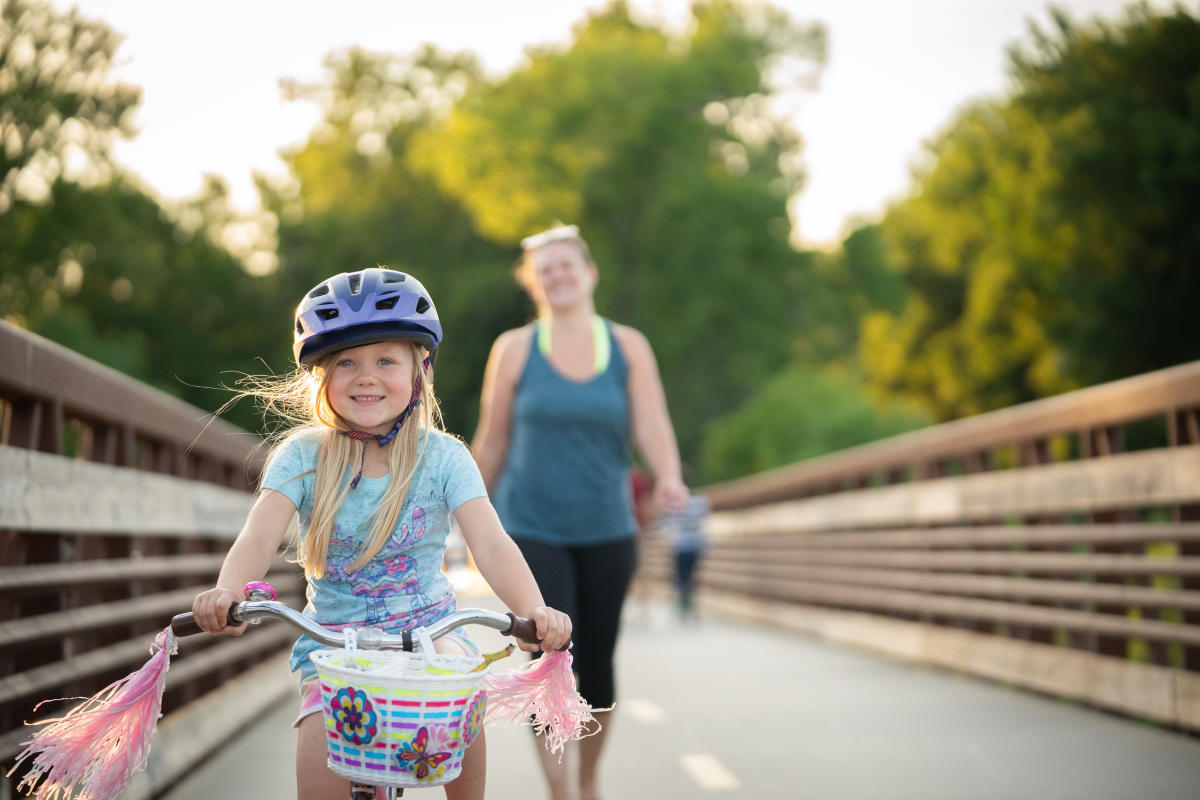 A girl rides her bike over the Lower Yahara River Trail bridge
