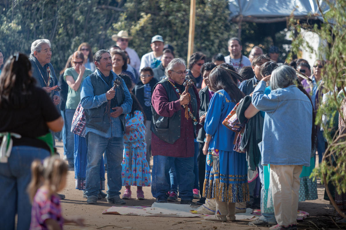 Medicine men deliver prayers while cooks prep a meal.