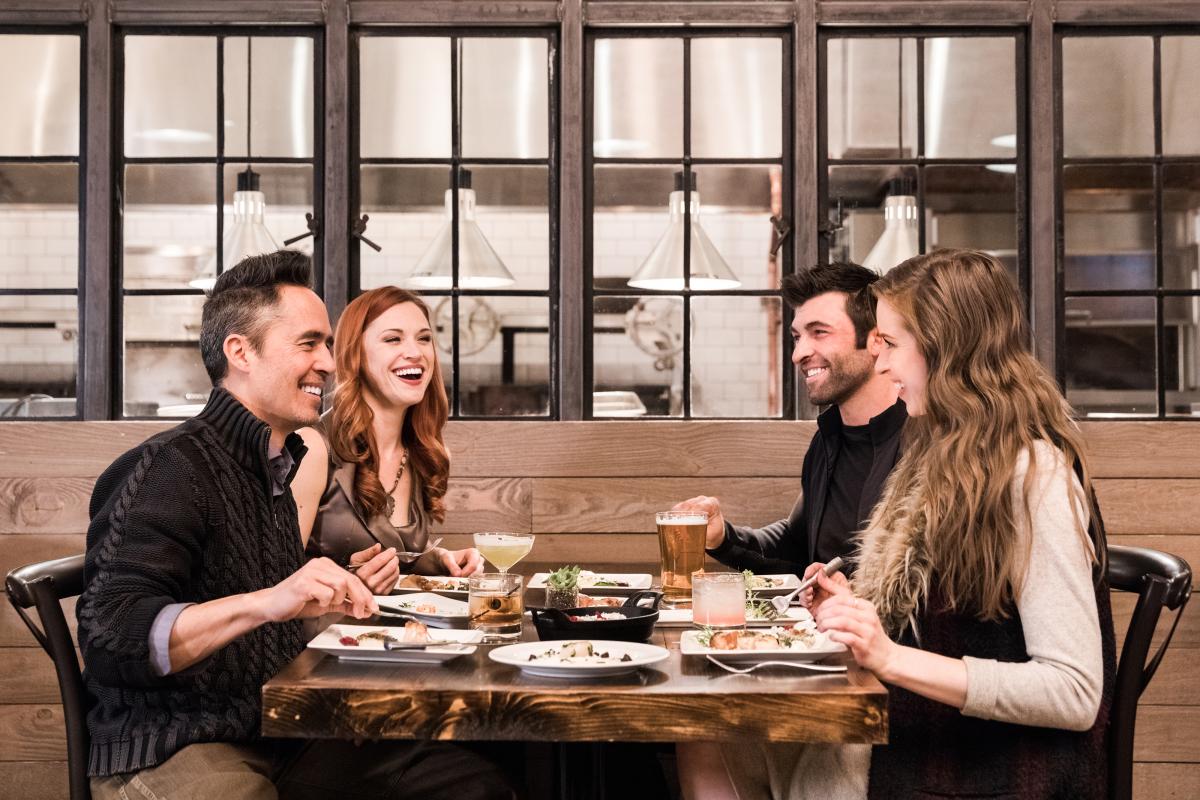 Four adults enjoying dinner at Firewood