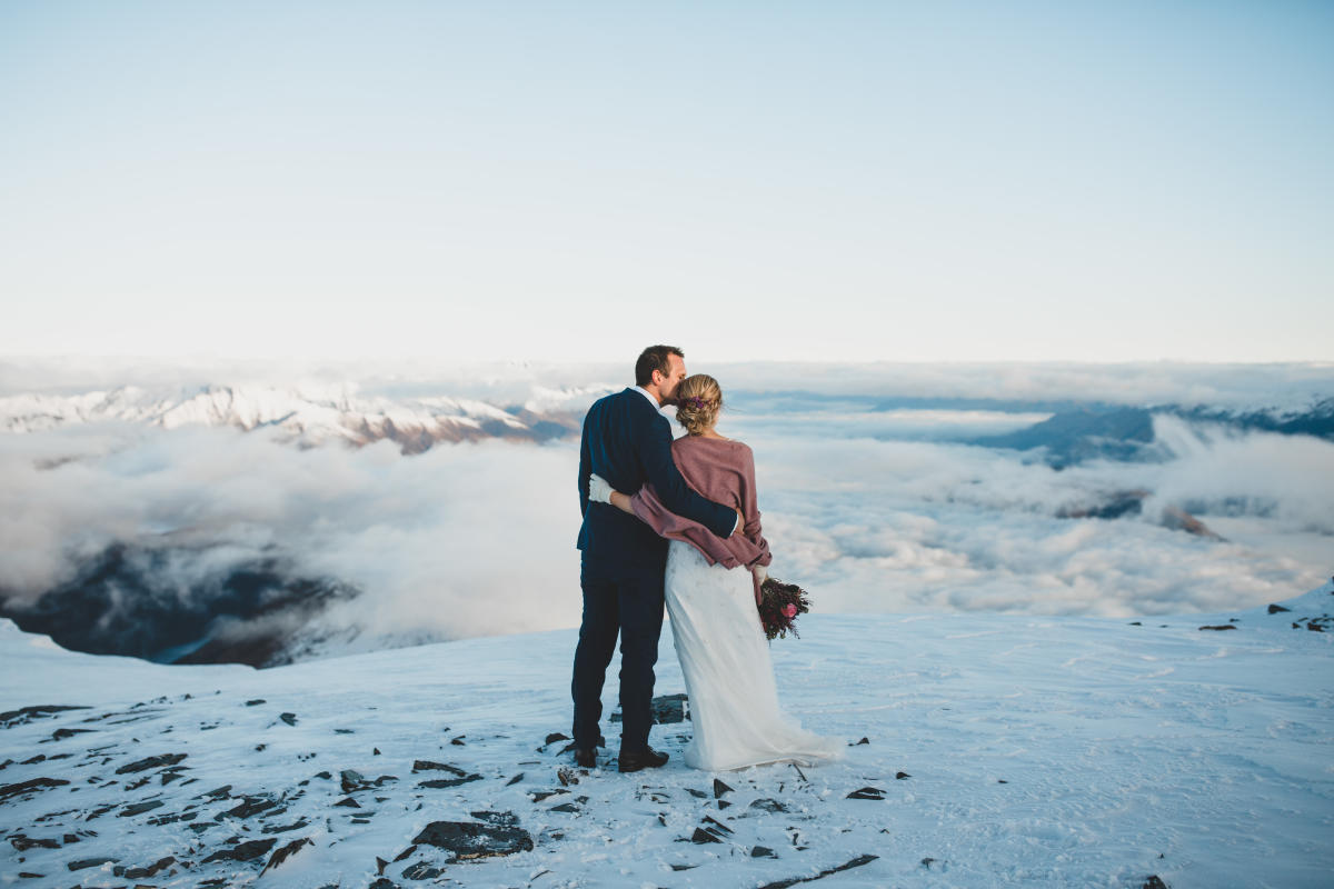 Married couple pose for wedding photo on top of mountain near Queenstown, New Zealand