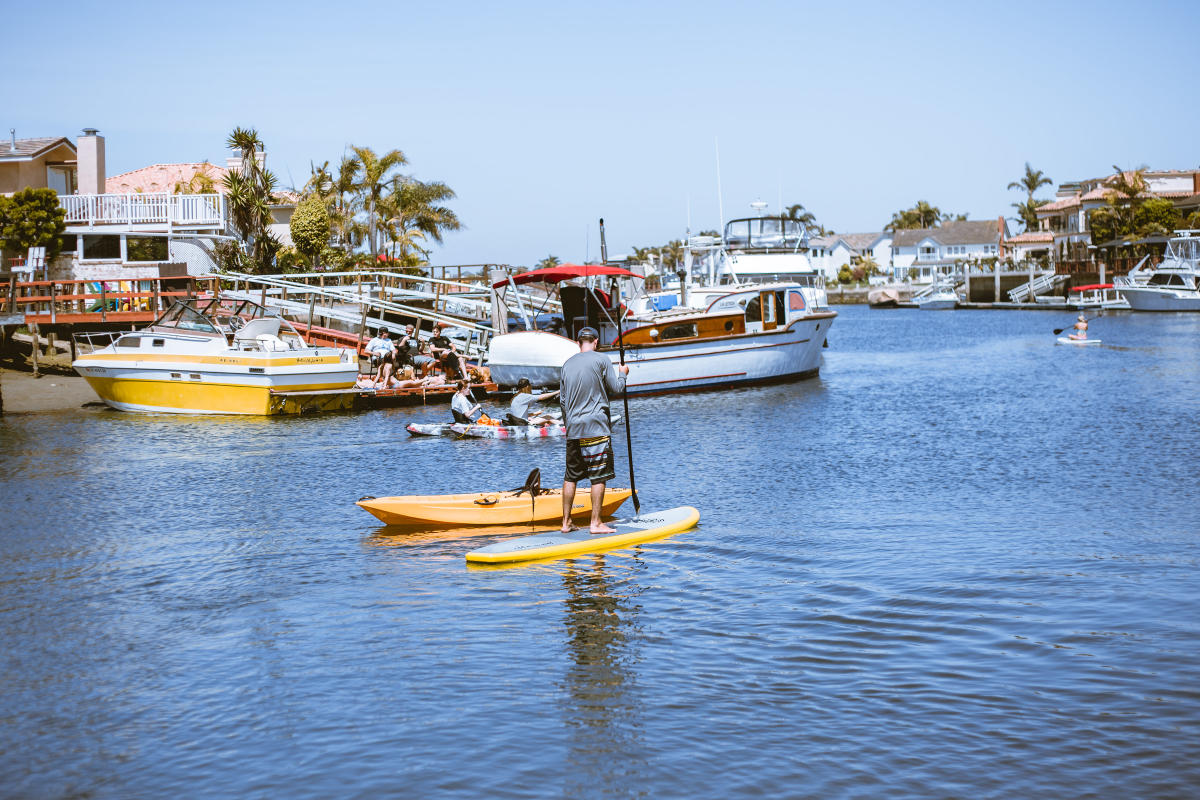 Man stand up paddle boarding through Huntington Harbour