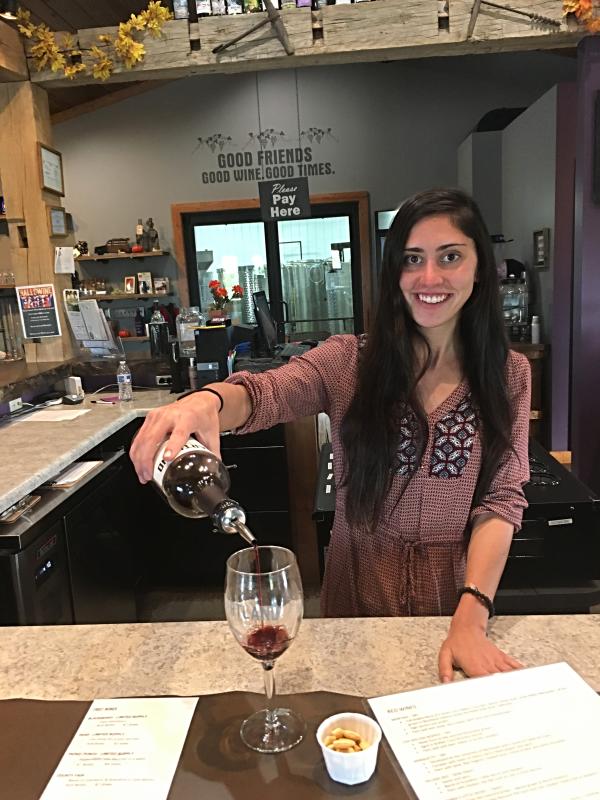 Kristen pours a glass of wine for a wine taster at Hartland Winery in Ashley.