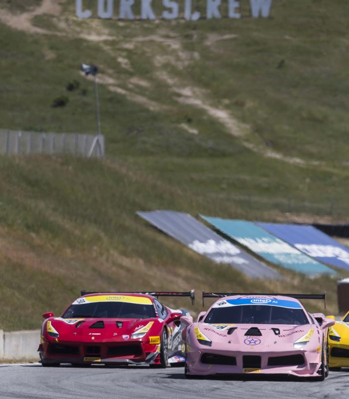 Cars racing at WeatherTech Raceway Laguna Seca with the Corkscrew sign in the background