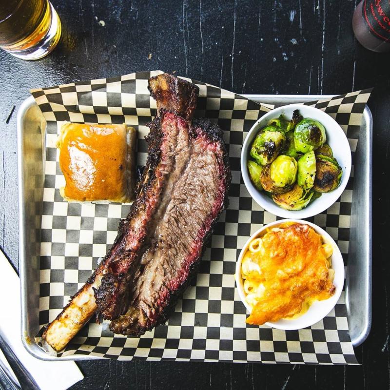 BBQ, buttered roll and more food from Smokin Woods BBQ on a black and white checkered tray