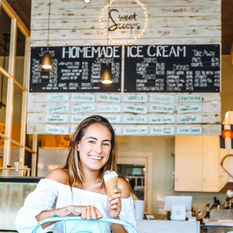 Young woman smiling on a chair while eating Sweet Scoops Ice Cream in Sonoma