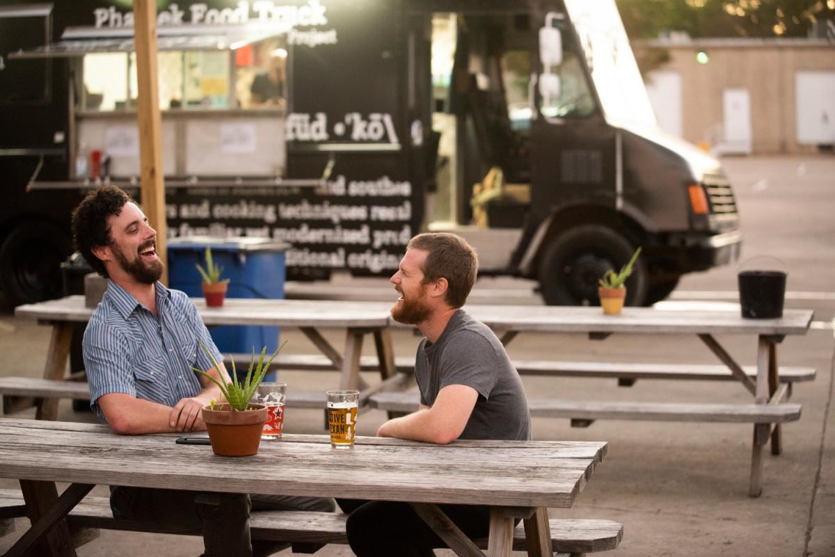 Local musician Doctor JOE and bandmate laugh while drinking beer at food truck in austin texas