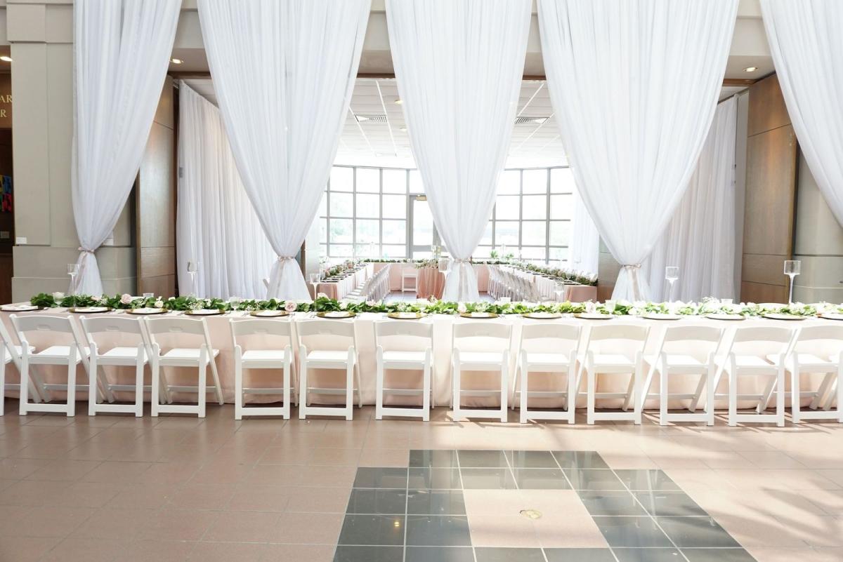 Large Row Of Dining Tables With White Plates And Table Cloths