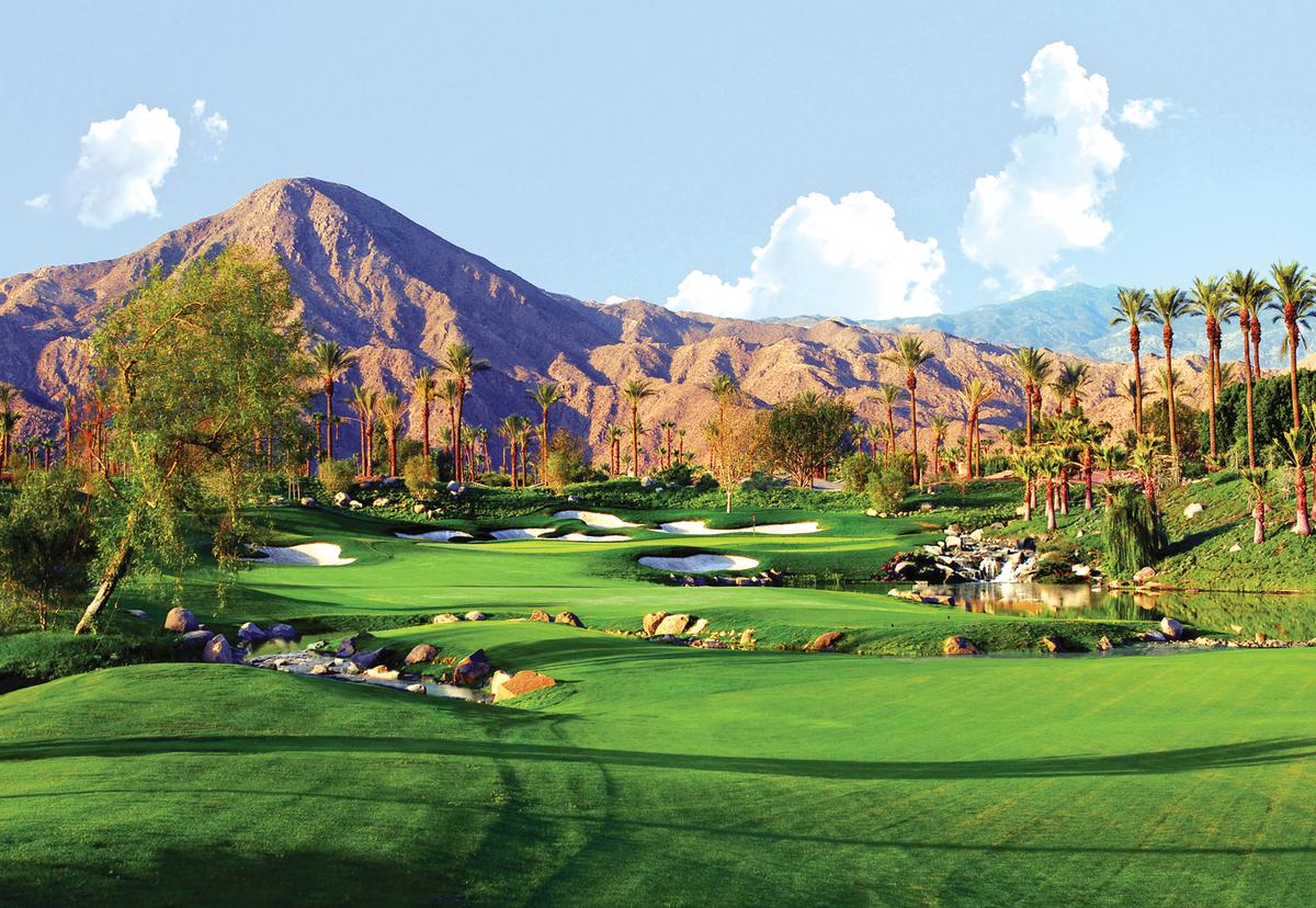 Green golf course against mountains and palm trees