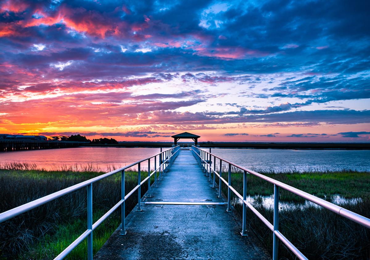 A sunset paints the sky over the marshes at Gascoigne Bluff Pier