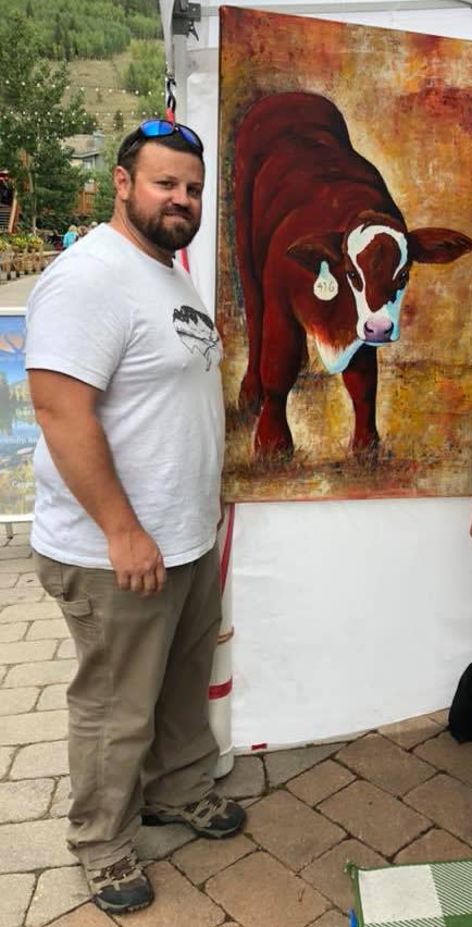 Artist Steve Knox standing beside his painting of a cow.