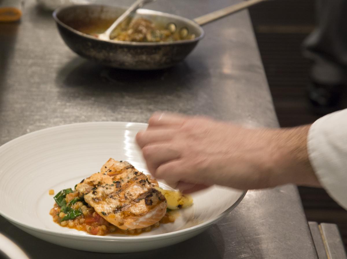 Chef adds finishing touches to Biba Restaurant Dine Downtown 2017 dish: Salmone con Frecola e Pomodoro - Grilled salmon on a bed of fregola stewed in fennel and tomatoes. Taken 1/3/2017