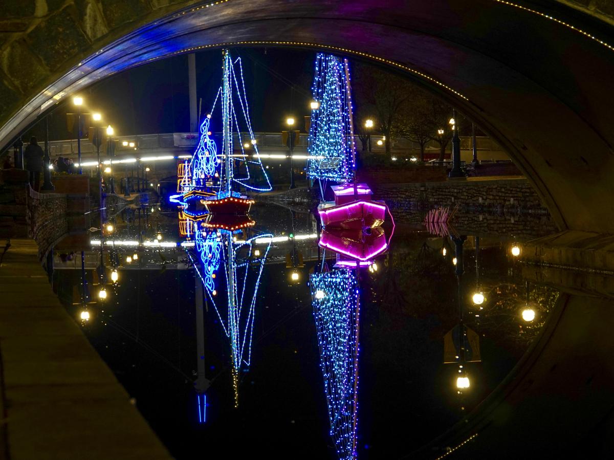 Boats floating in Carroll Creek covered in lights at night 