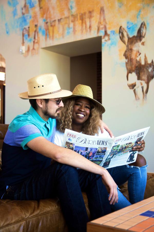 Couple Reading A Newspaper At Texican Court In Irving, TX