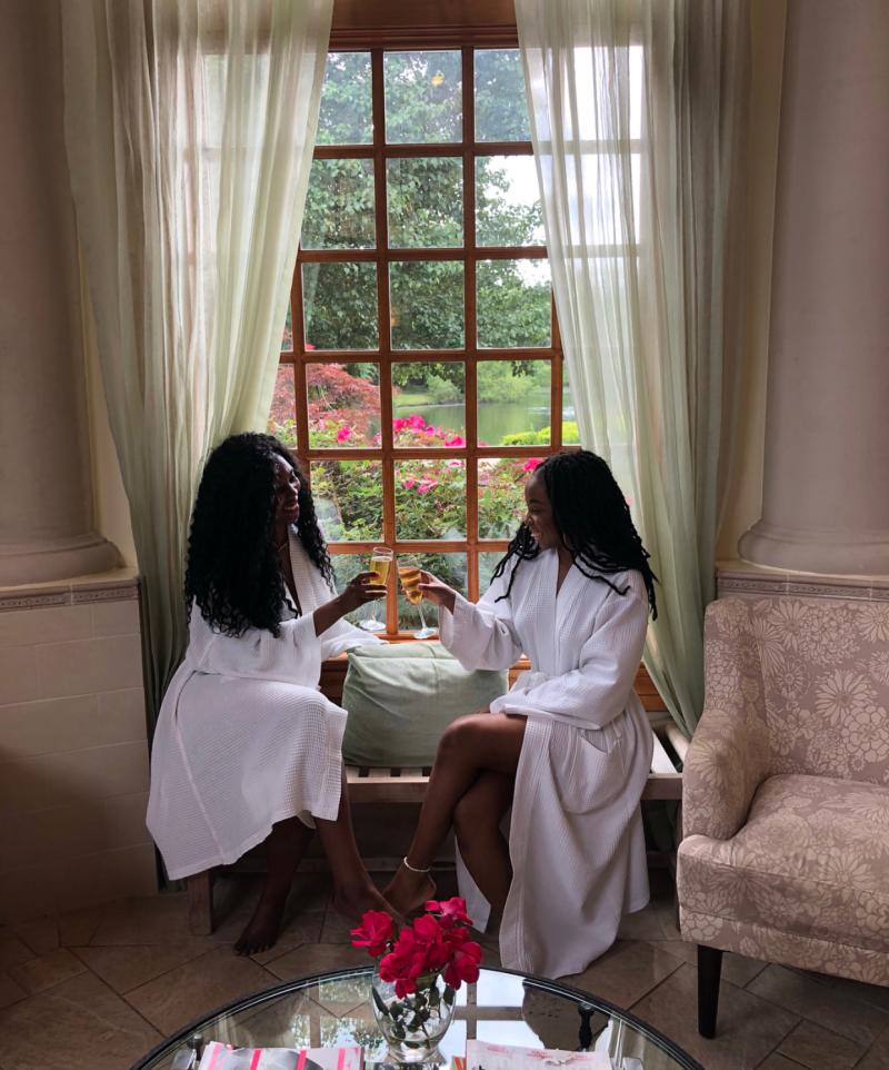 Two women cheers with champagne in robes during a day at Flowering Almond Spa