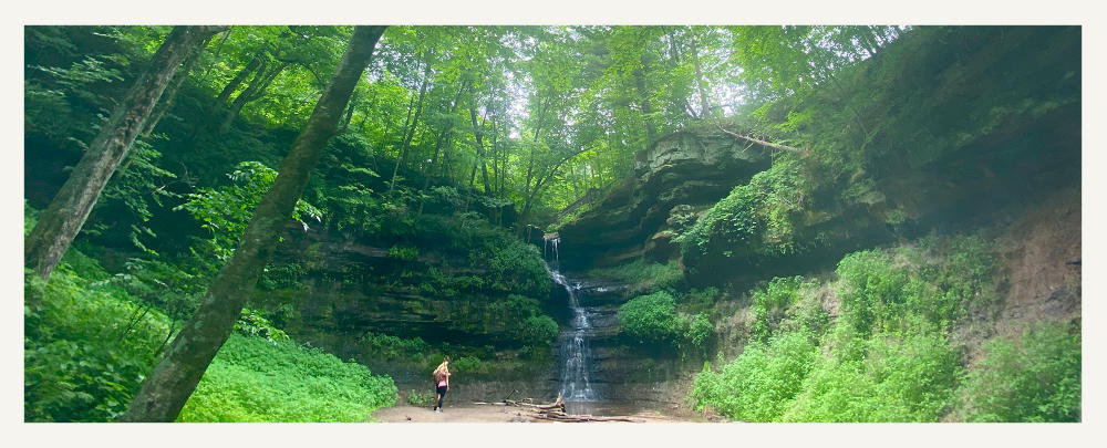 Person standing at the foot of a waterfall Devil's Punchbowl in Menomonie, WI