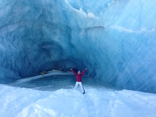 A woman and a dog stand in an ice cave at Valdez Glacier Lake