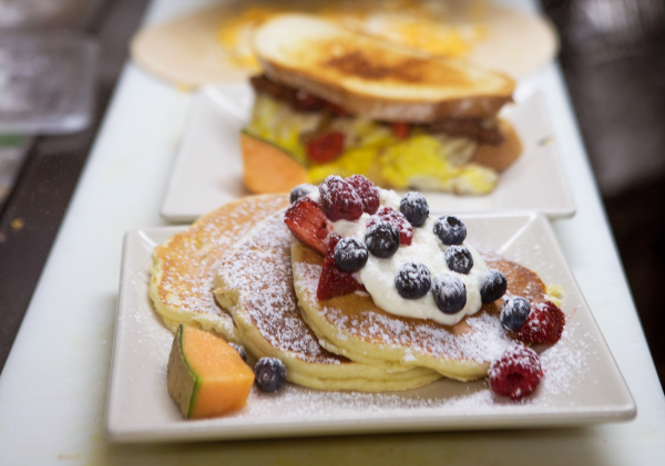 Stack of pancakes topped with whipped cream and fresh fruit at the French Press