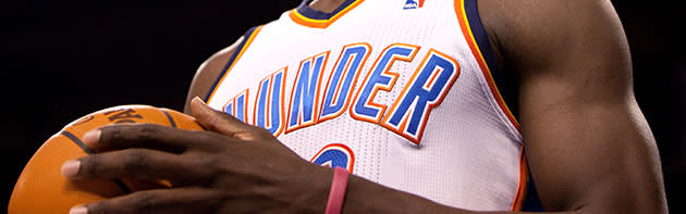 Man holding basketball in a Thunder uniform