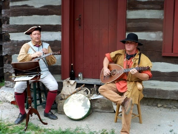 Re-enactors can't forget about the musical side of history. Two men in 1770s clothing play musical instruments