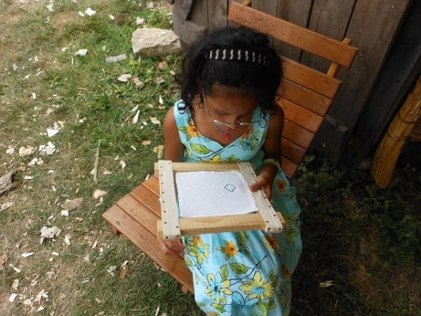 This girl is really interested in her historic craft! A little girl does some sewing
