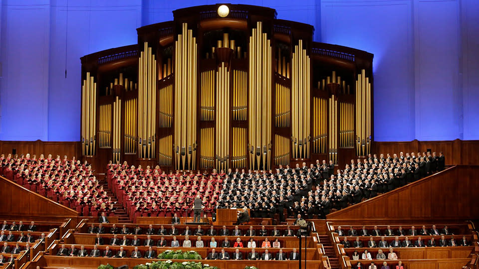 The Tabernacle Choir sings on a stage in front of a giant pipe organ in Salt Lake City, UT.