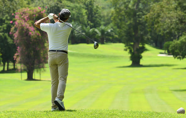 A man hits a tee shot in a game of golf