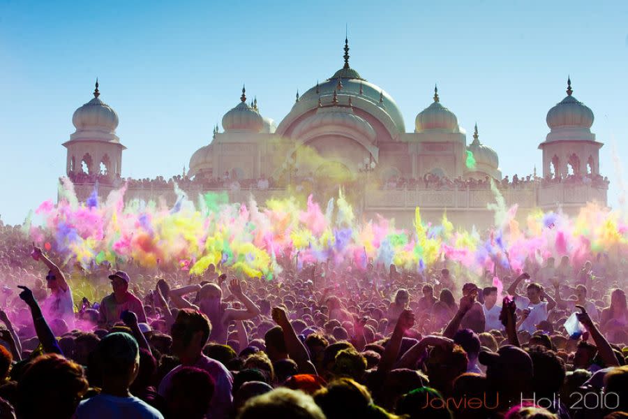 crowd throws colored chalk in the air in front of Hindu temple