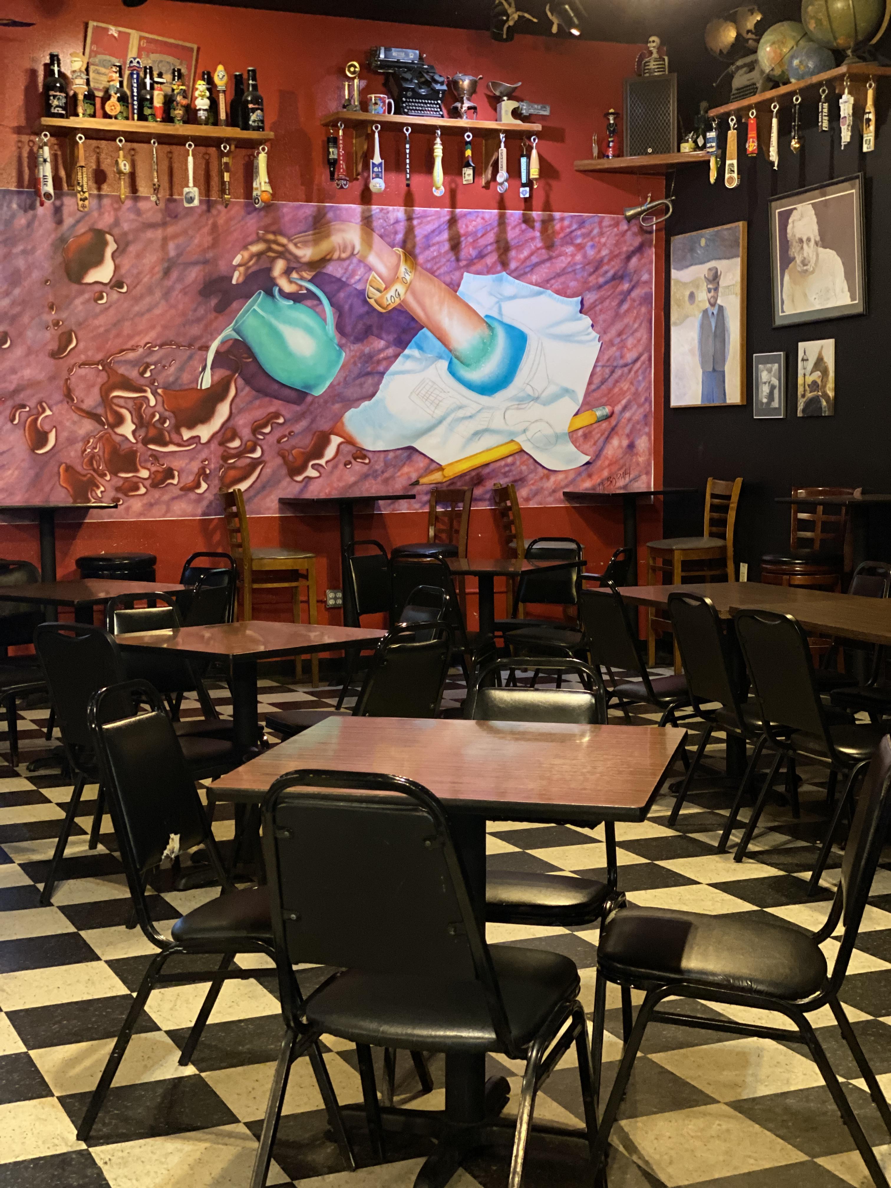 dining area of Logon Cafe with mural of hand pouring wine from pitcher