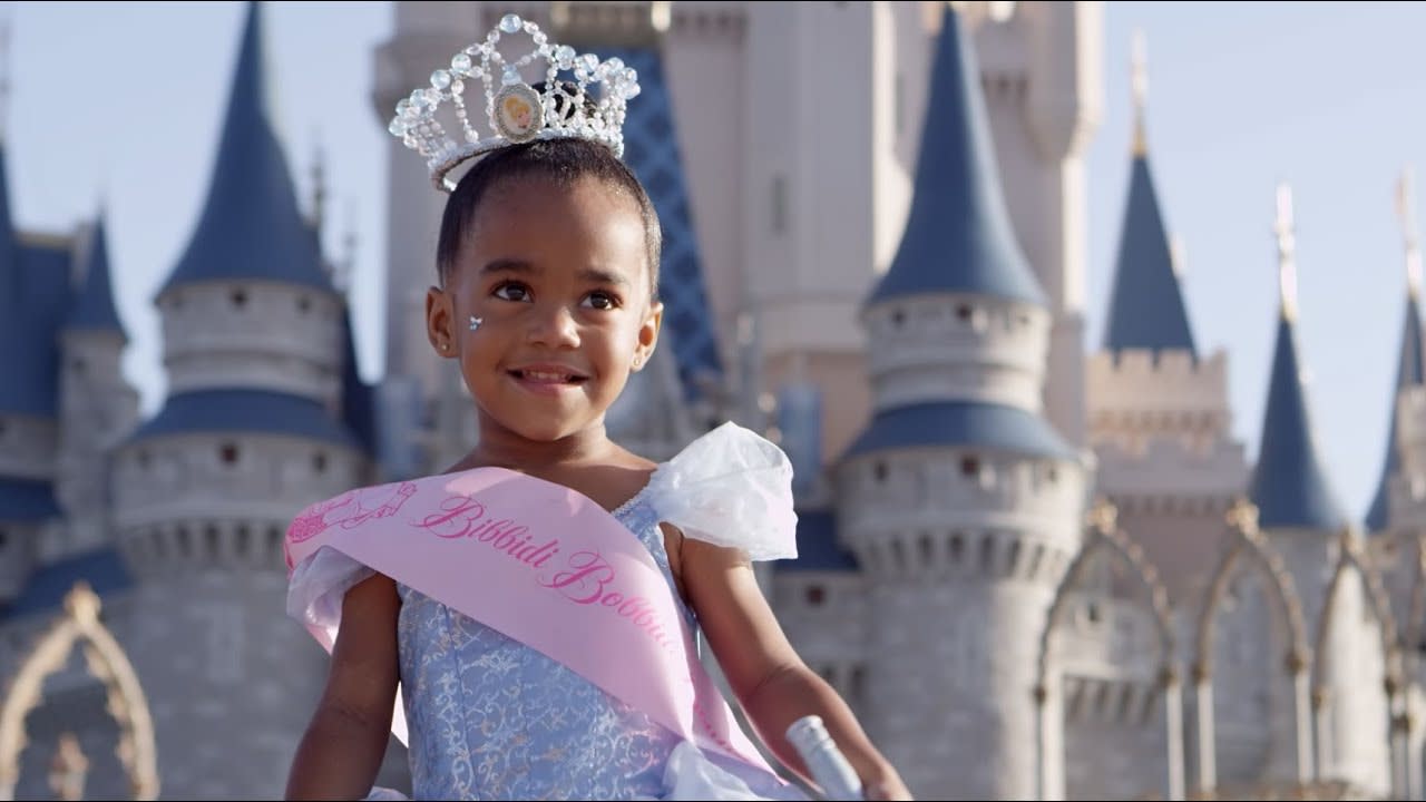 a little girl dressed up as a princess in front of Disney Magic Kingdom castle