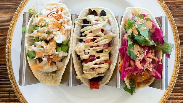 View from above of three tacos, each filled with different ingredients