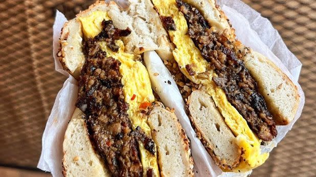 Breakfast sandwich cut in half showing egg, faux-meat and bagel