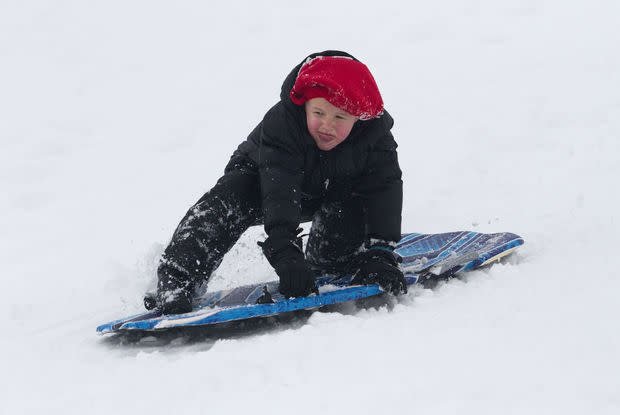 Little boy trying to stand up on his sled