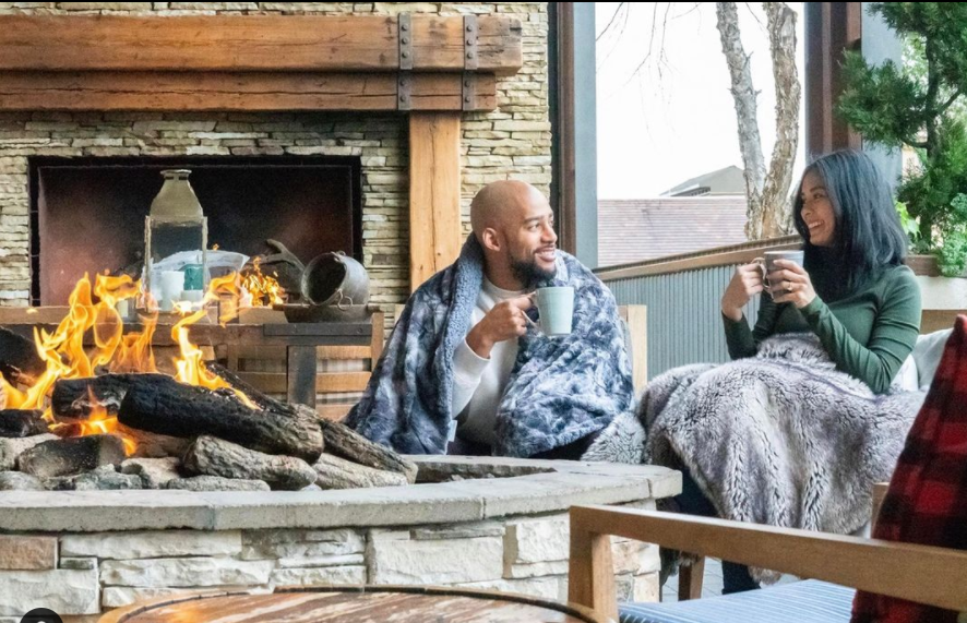 Couple snuggled under blankets sitting by the outside fire at the Four Seasons Resort at Las Colinas