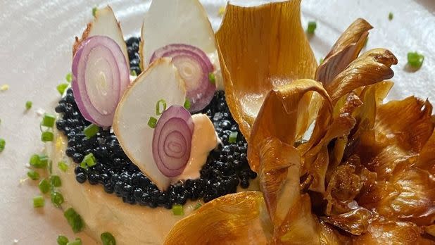 Elegant plate of food topped with caviar, onions, garnish