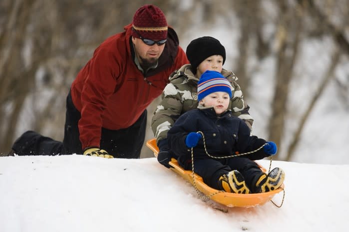 Father pushes his children's sled down the hill