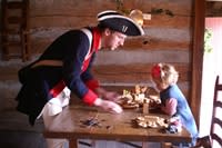 Kids and historical re-enactors work on crafts at the Christmas at the Fort