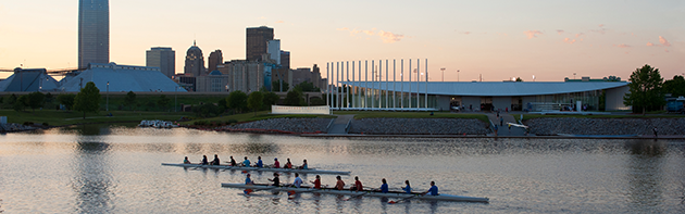 Image of the Oklahoma City Skyline, in the foreground are rowers rowing in the Oklahoma River.