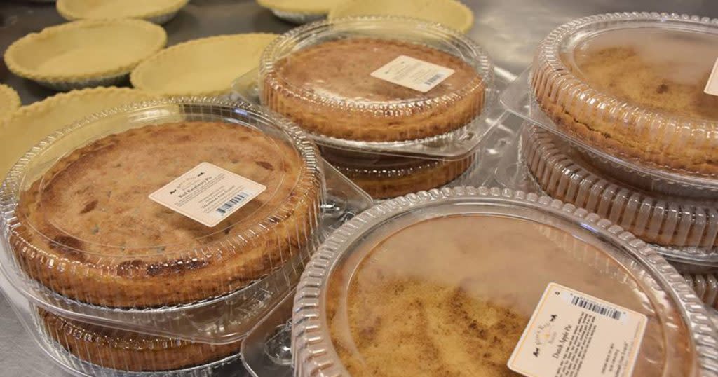 Plastic shells filled with pies are stacked two- and three-high next to a group of unbaked pie shells at Rise 'n Roll in Middlebury, IN