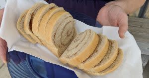A hand holds a basket of fresh-baked bread from the Carriage House in Topeka, IN