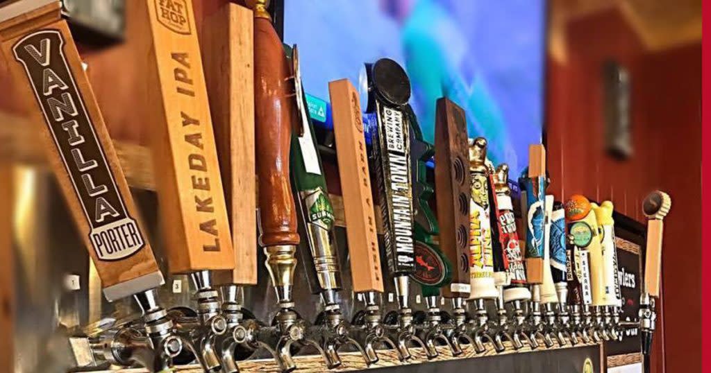 Close-up of a row of unique bar taps in front of an out-of-focus flat screen TV