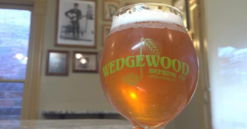 Close up of a glass of beer with a thick head - the glass says "Wedgwood" on the front