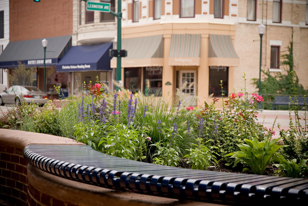 Close-up of a curved metal bench with a flower bed in downtown Elkhart, Indiana.