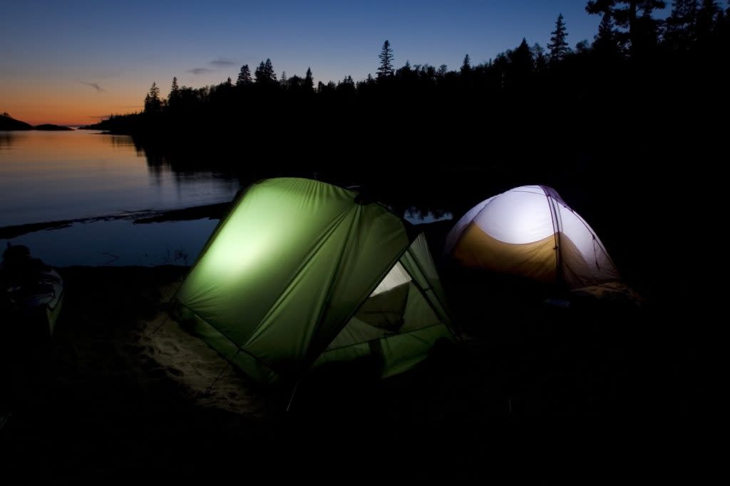 A pair of tents glow at dusk during a sea kayaking trip at Chalfant Cove in Lake Superior Provincial Park near Wawa Ontario Canada.