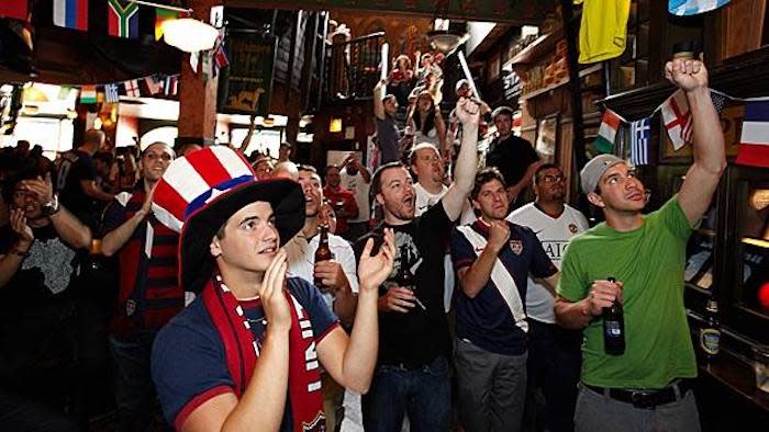 A group of people cheering inside a pub