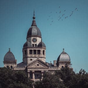 Denton's Courthouse-on-the-Square with a blue sky and a flock of bird flying above it