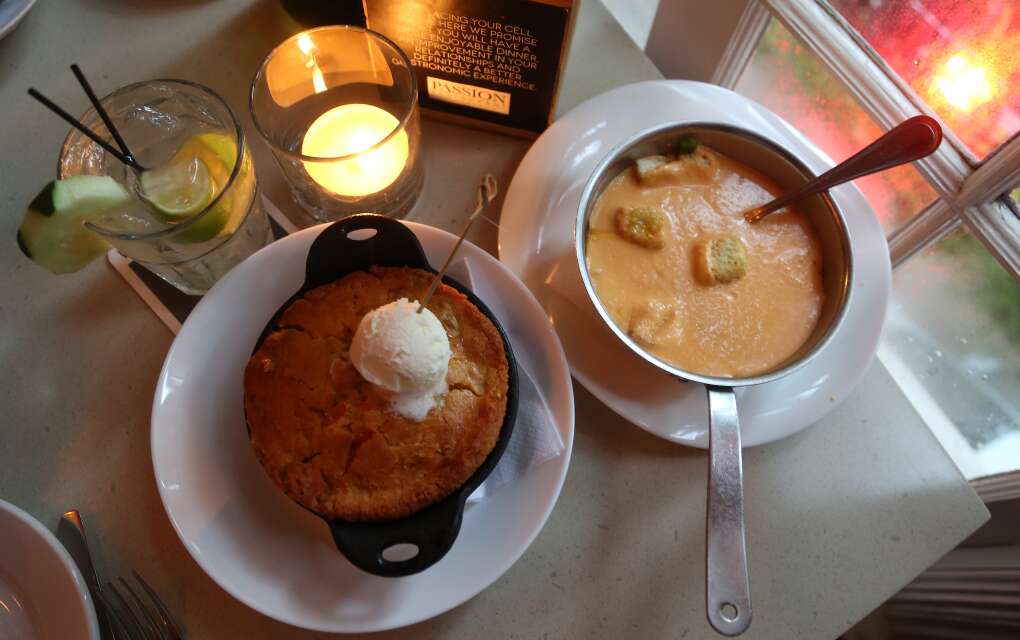 buttered cornbread in a iron skillet with a bowl of soup with crouton