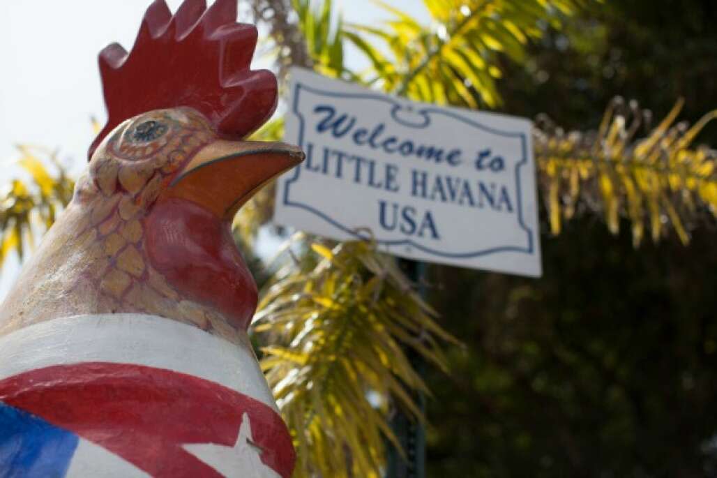 a rooster sculpture in front of a sign saying welcome to little havana