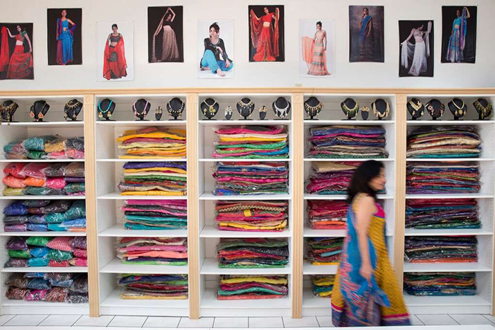 Co-owner and designer Amita Patel passes by her brightly colored traditional Indian outfits inside her store Vulcal Boutique in Orlando, which offers everything from bridal lehenga cholis to everyday  saris.