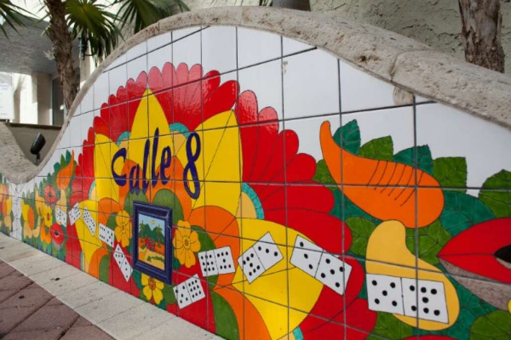 a wall decorated with tiles showing dominoes and flowers and saying calle 8