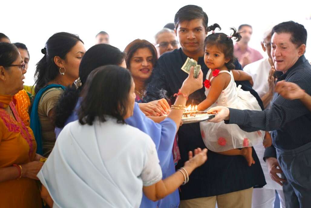 With his wife, Sapna Goyani, beside him, Kartik Goyani holds his 2-year-old daughter, Kiara, during a prayer service at the Jain Temple in Tampa on a Sunday morning. 